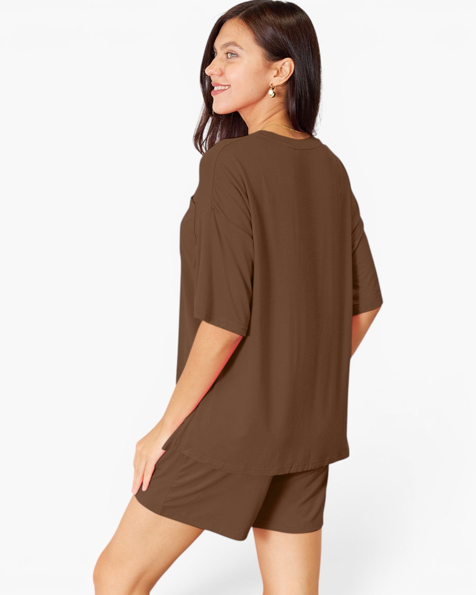 A woman modeling an oversized short-sleeve brown t-shirt and matching shorts against a plain white studio background.