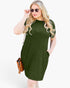 A woman modeling a short-sleeve olive green shift dress with side pockets, styled with sunglasses and a brown crossbody bag against a plain white background.