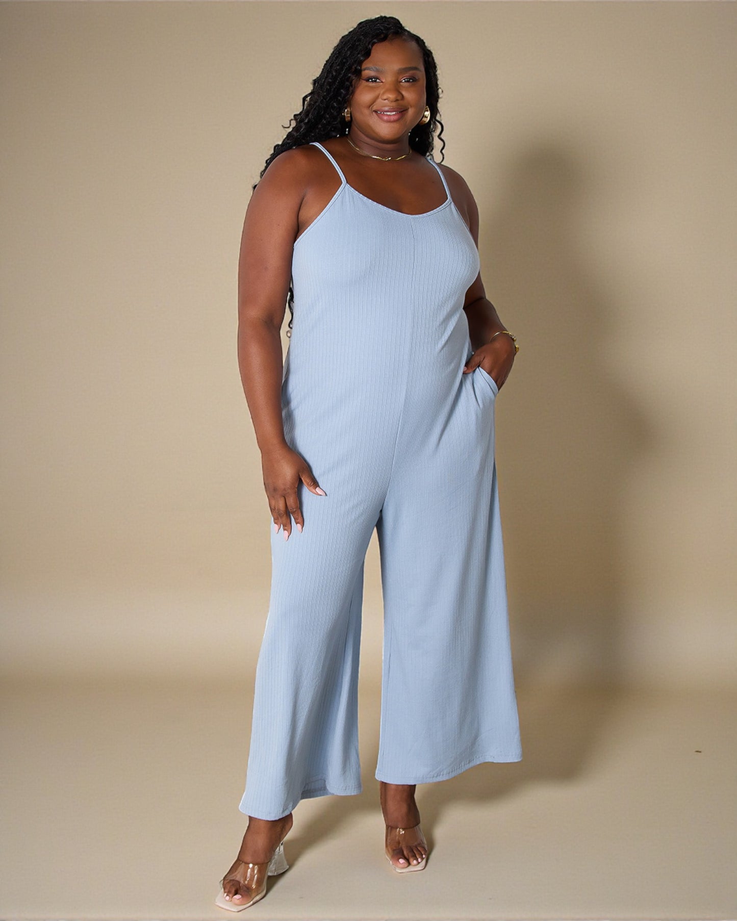 Woman wearing a light blue jumpsuit against a beige background