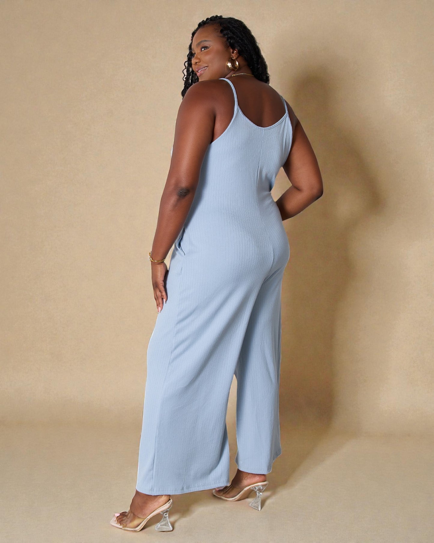 Woman wearing a light blue jumpsuit against a beige background