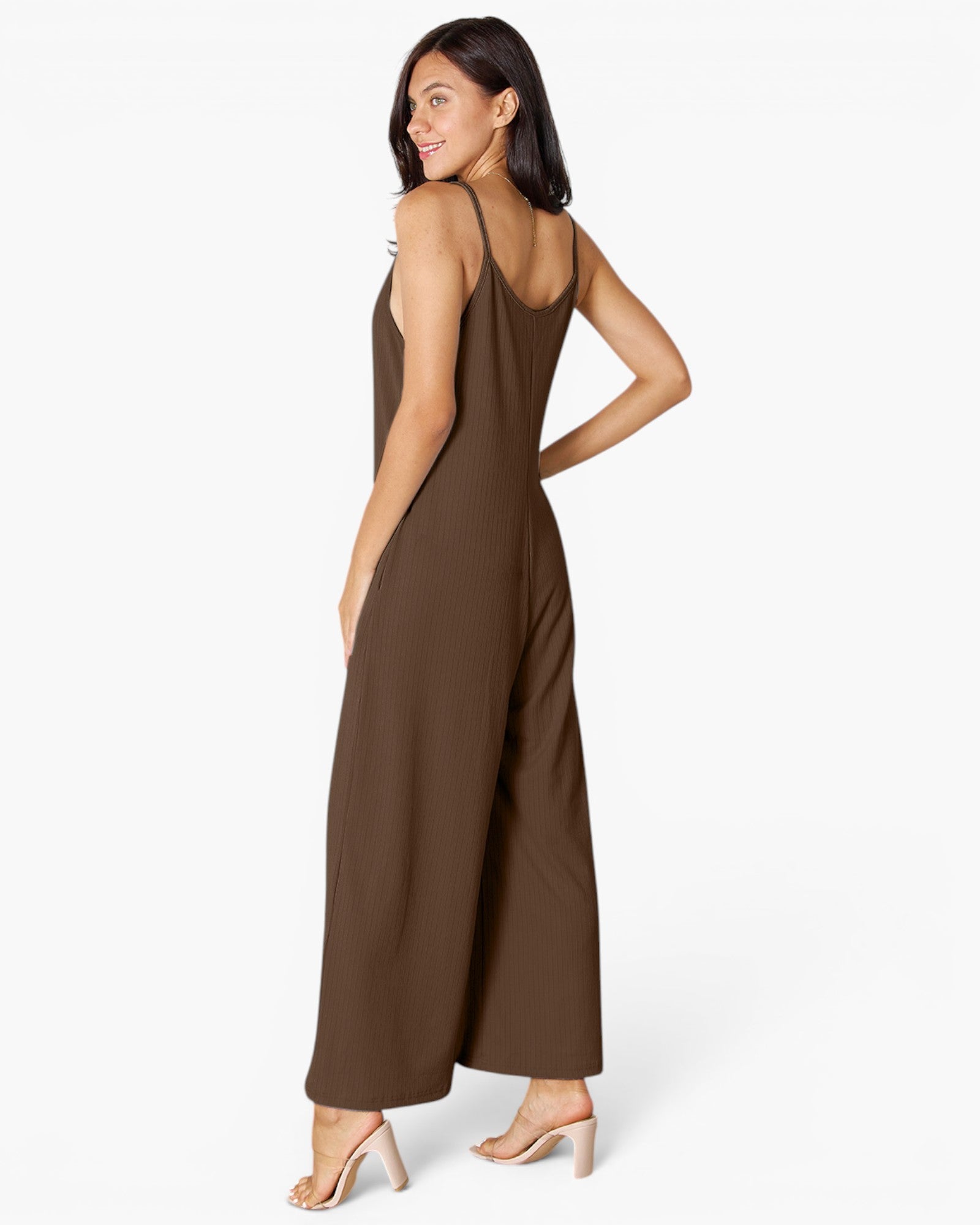 A woman modeling a sleeveless, wide-leg brown jumpsuit from the back, shown against a plain white studio background.