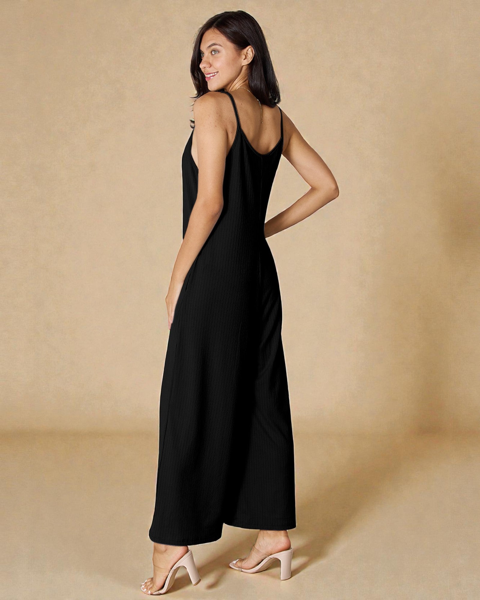 Woman wearing a black sleeveless dress against a beige background