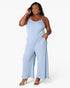 A woman modeling a light blue sleeveless jumpsuit with wide legs and thin shoulder straps, standing against a plain white studio background.