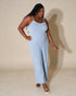 Woman wearing a light blue jumpsuit against a beige background