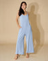 Woman wearing a light blue jumpsuit against a beige background
