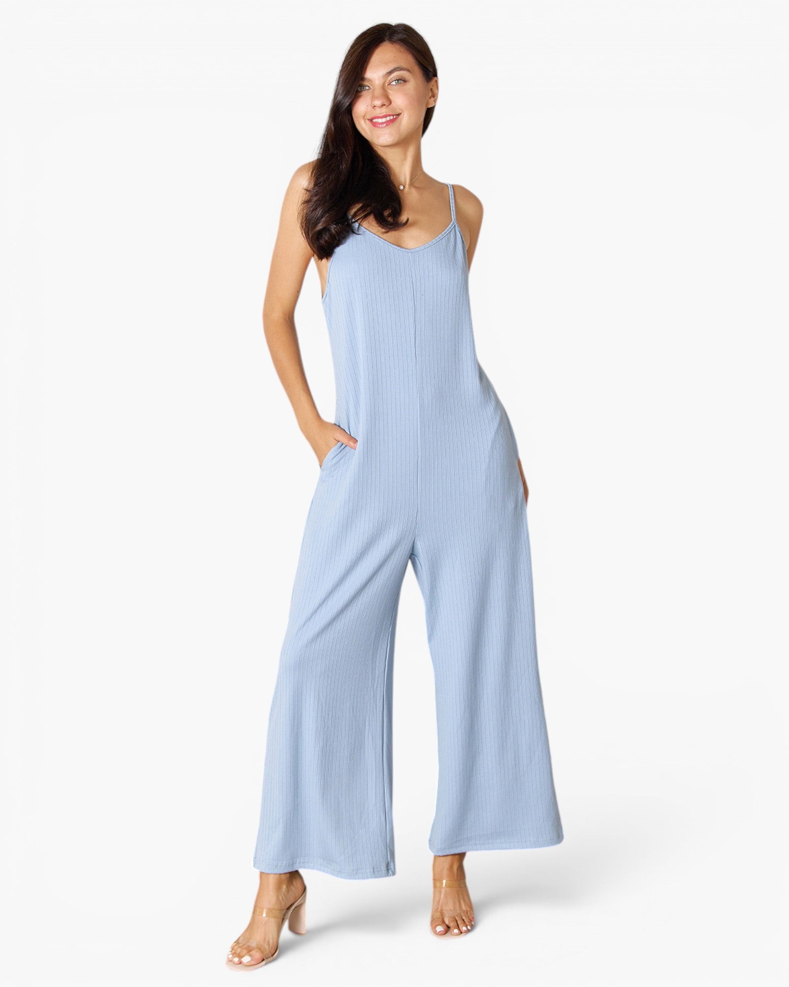 A woman modeling a light blue sleeveless jumpsuit with wide legs and thin shoulder straps, standing against a plain white studio background.
