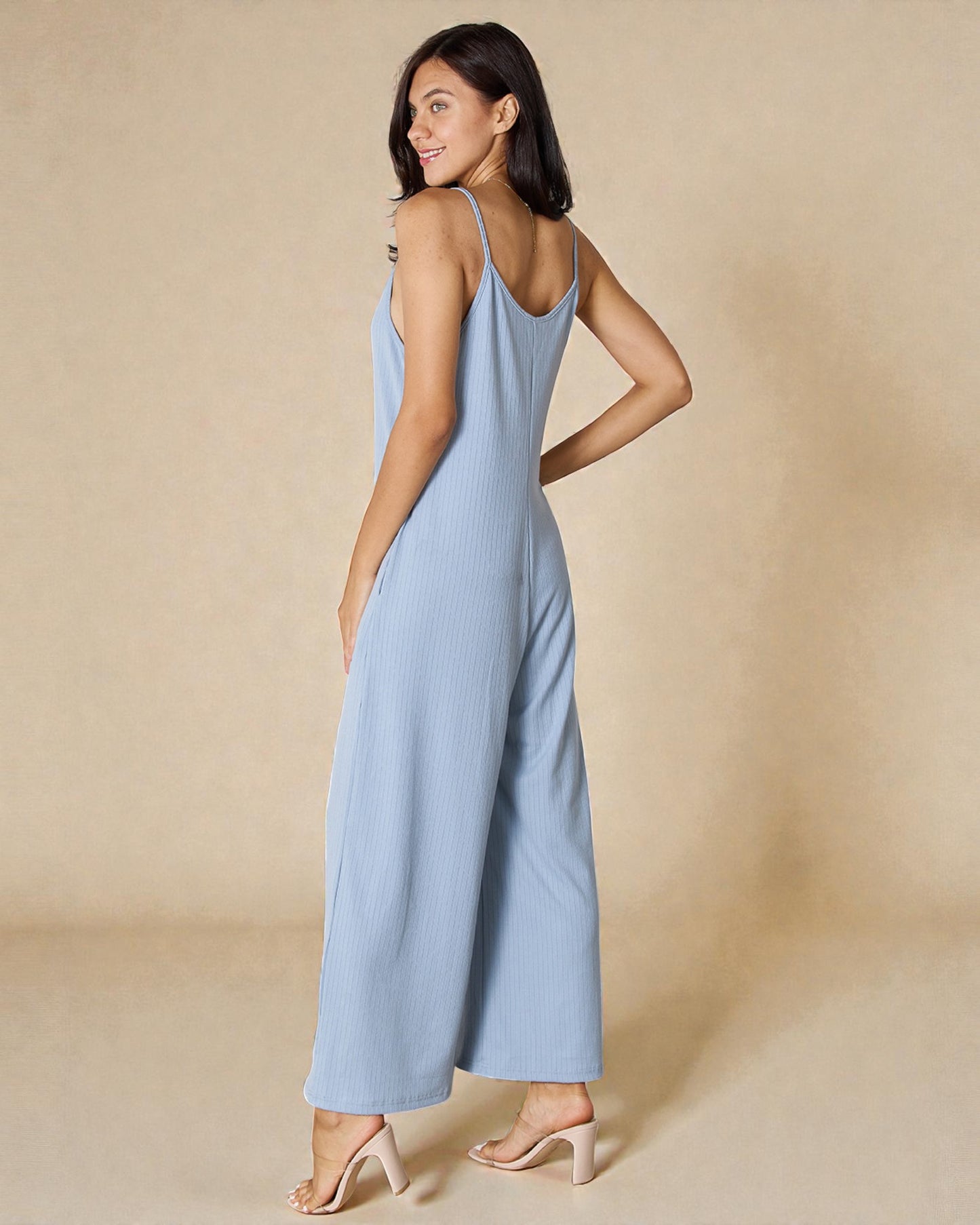 Woman wearing a light blue jumpsuit against a beige background