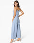 A woman modeling a light blue sleeveless wide-leg jumpsuit, shown from a side-back angle against a plain white studio background.