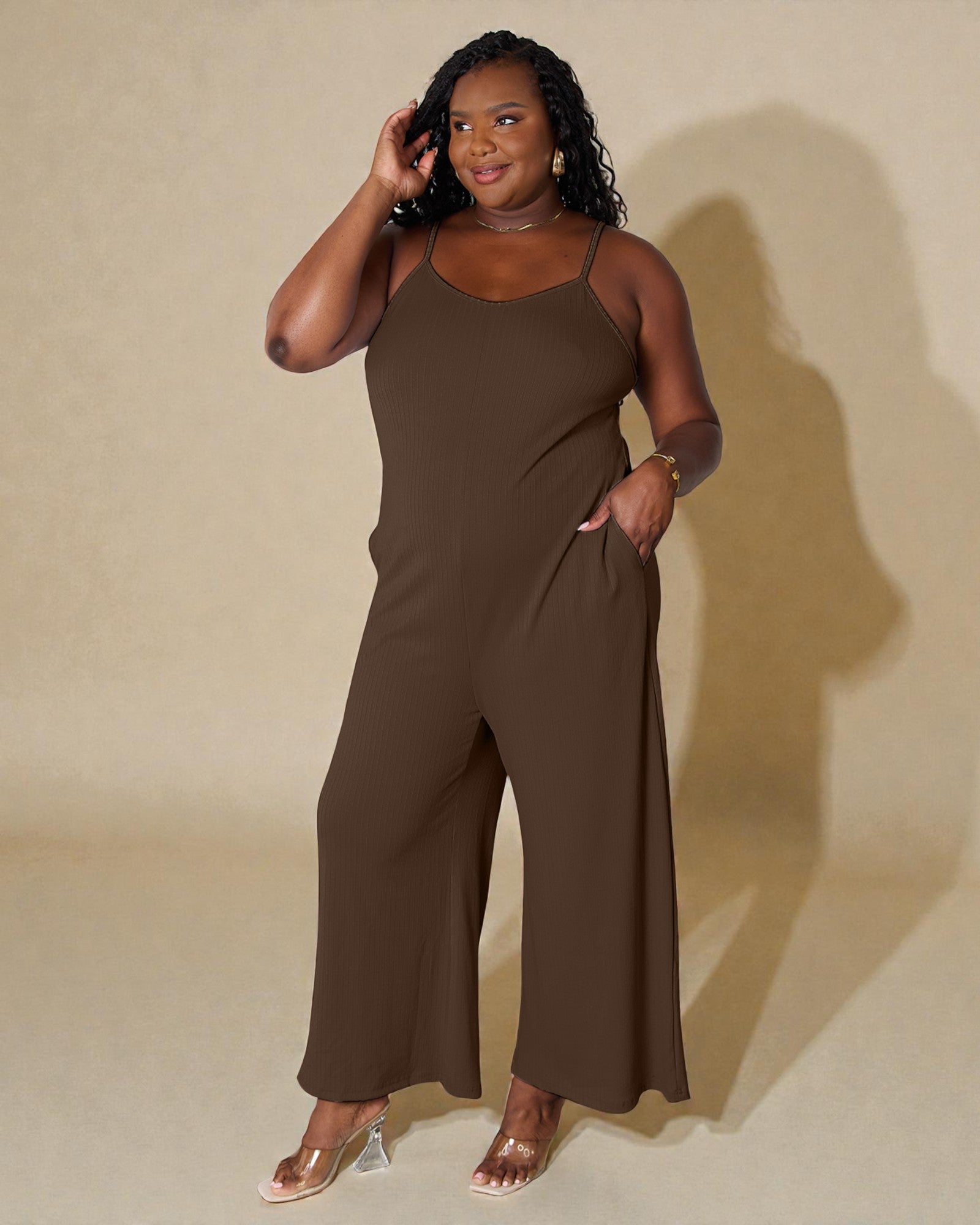 Woman wearing a brown jumpsuit against a beige background