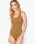 A woman modeling a solid tan one-piece swimsuit against a clean, light gray studio background.