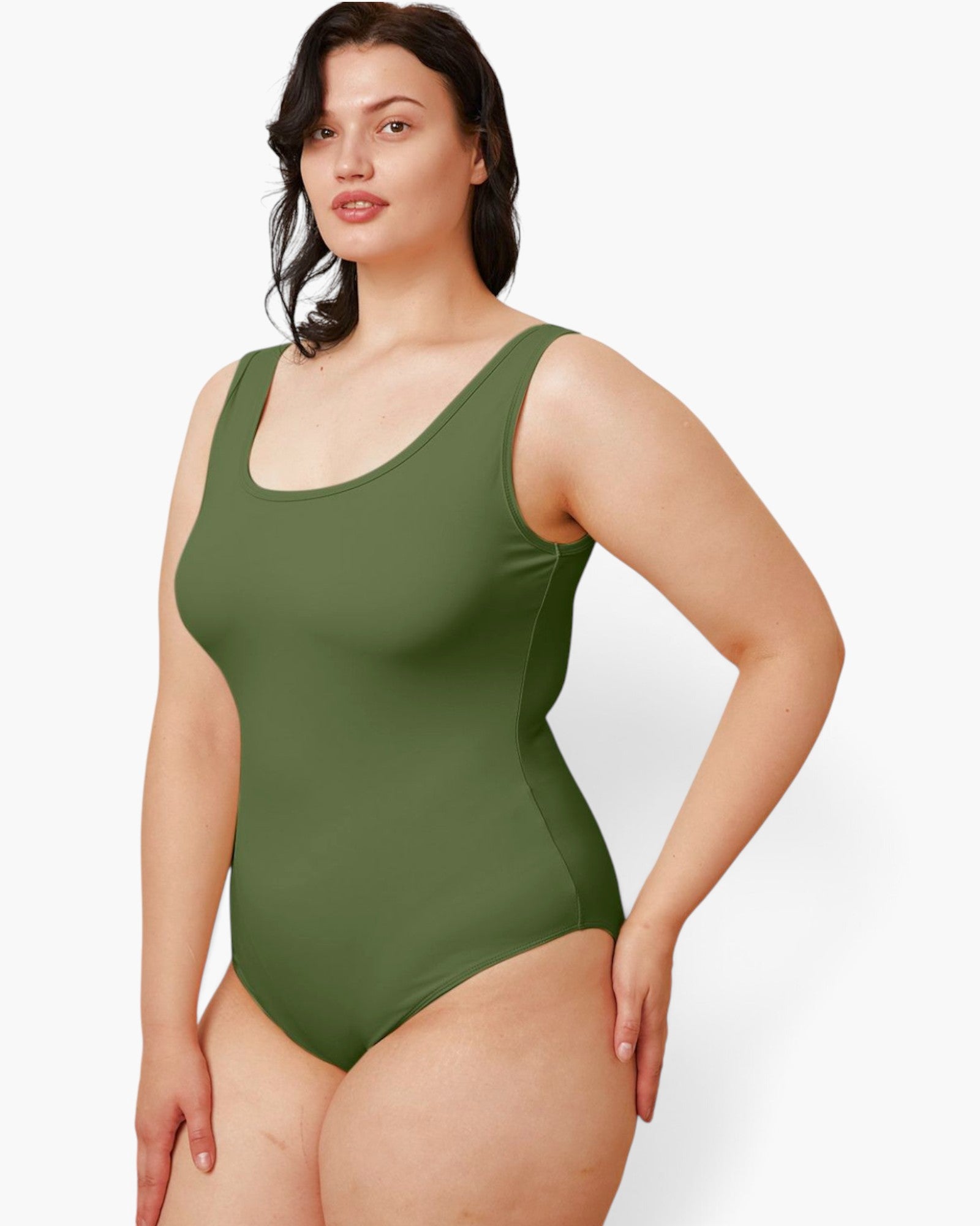 A woman modeling a solid olive green one-piece swimsuit against a plain light gray studio background.
