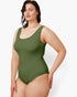 A woman modeling a solid olive green one-piece swimsuit against a plain light gray studio background.
