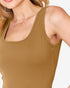 A close-up of a woman wearing a ribbed scoop-neck tank top in a warm camel brown color, paired with a delicate gold necklace.