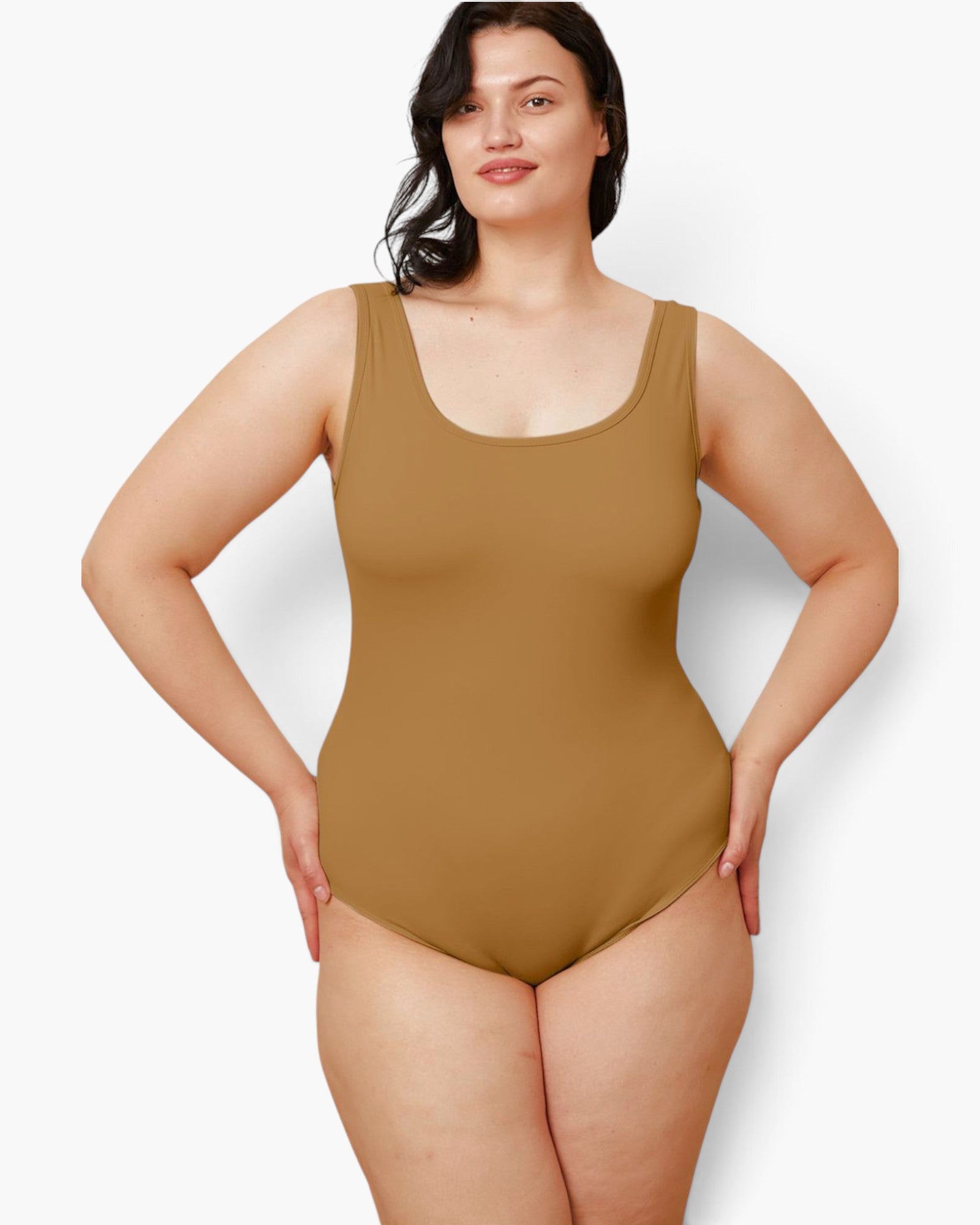 A woman modeling a sleeveless scoop-neck one-piece swimsuit in a solid tan color, posed against a light gray studio background.
