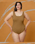 Woman wearing a brown swimsuit against an orange background