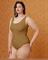 Woman wearing a brown swimsuit against an orange patterned background