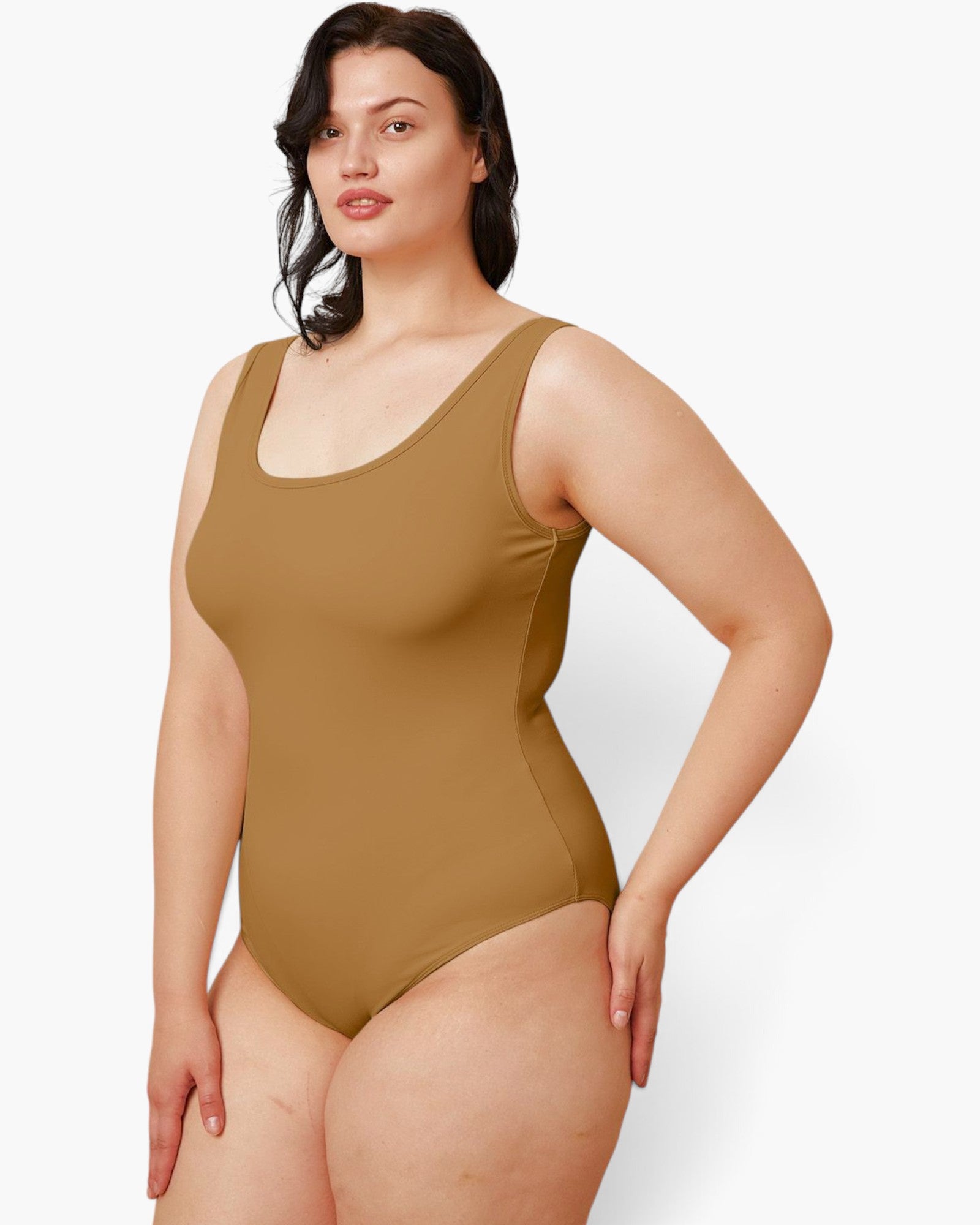 A woman modeling a sleeveless one-piece swimsuit in a solid tan-brown color, photographed against a clean white studio background.