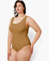A woman modeling a sleeveless one-piece swimsuit in a solid tan-brown color, photographed against a clean white studio background.