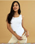 Woman wearing a white tank top and beige pants against a beige background