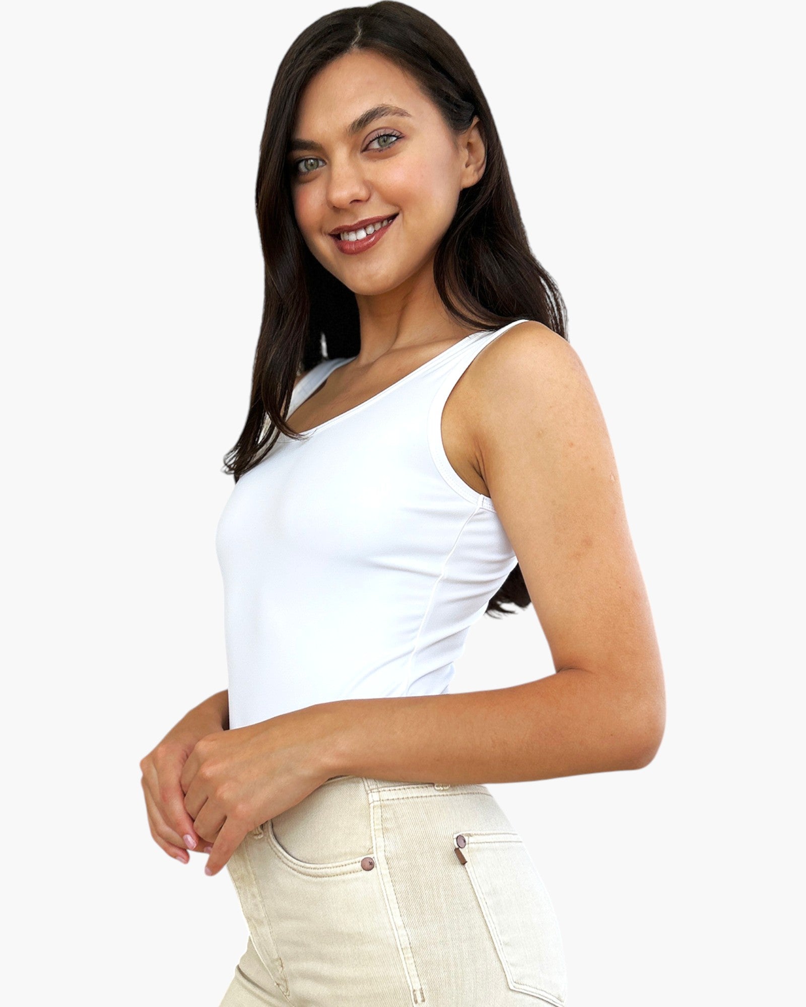A woman wearing a white sleeveless scoop-neck tank top and light beige jeans, photographed against a clean white background.