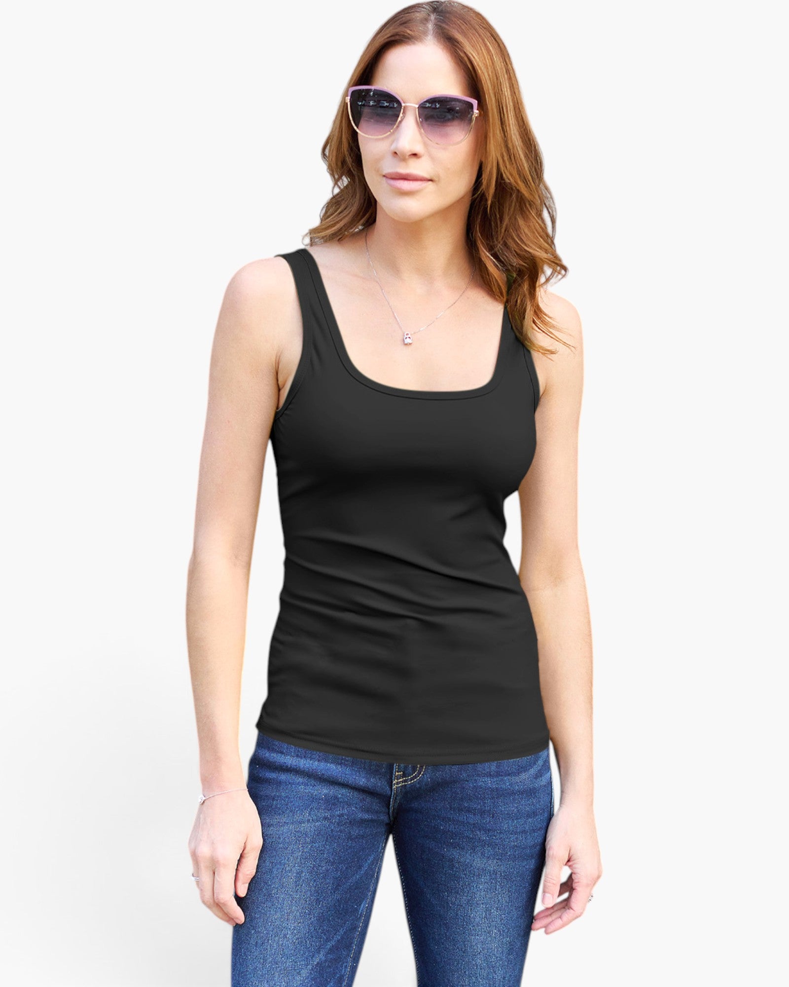 A woman modeling a black scoop-neck tank top with blue jeans and sunglasses against a plain white background.
