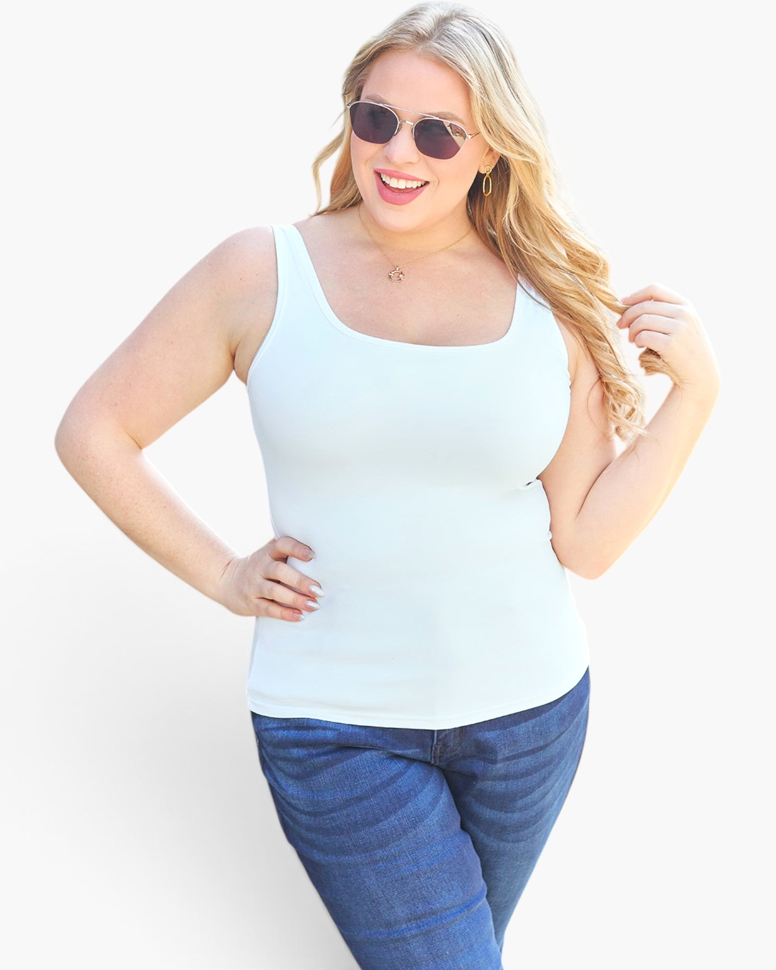 A woman modeling a light blue scoop-neck tank top with blue jeans against a plain white background.