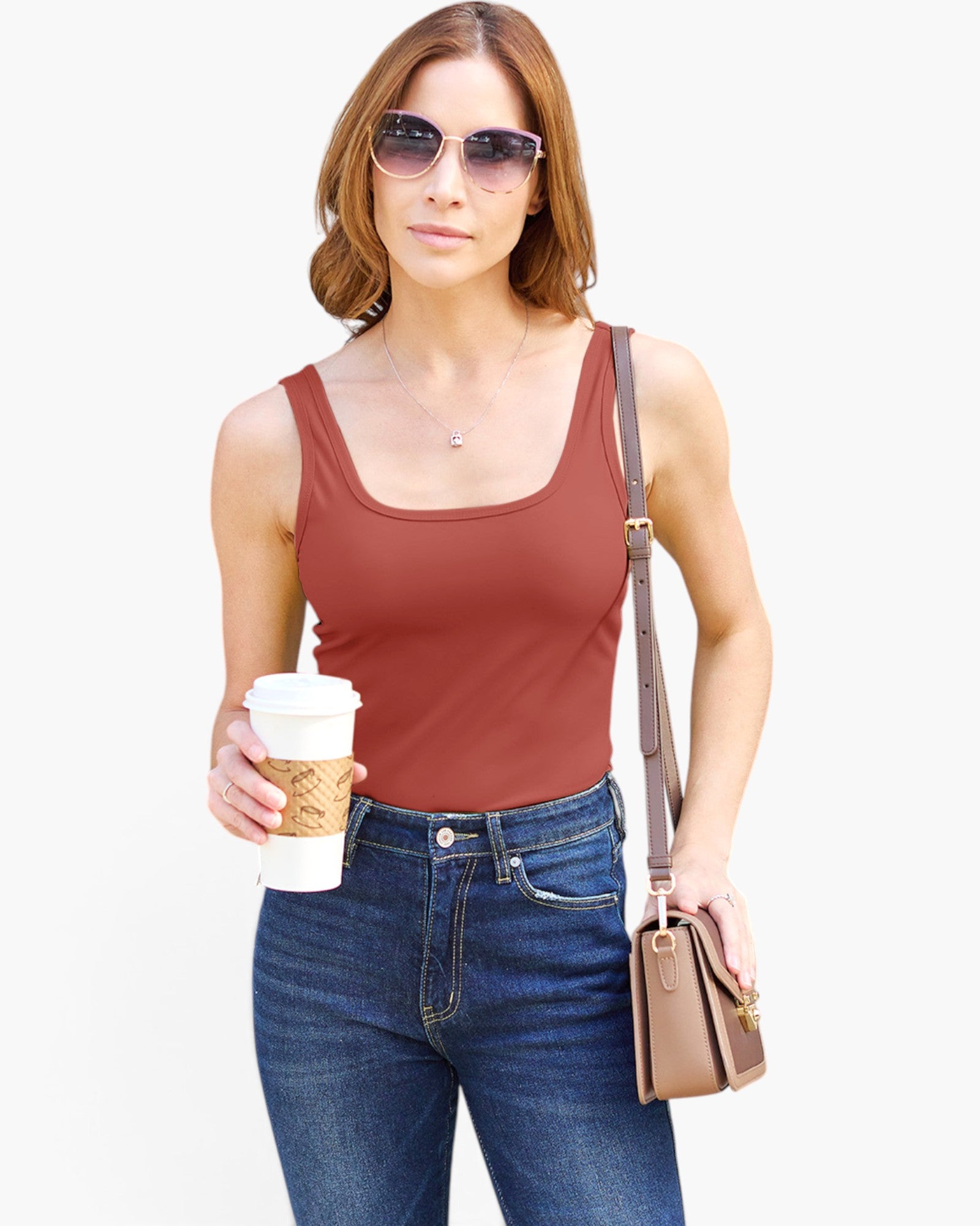 A woman modeling a rust-brown scoop-neck tank top with blue jeans, sunglasses, a small brown shoulder bag, and holding a coffee cup against a plain white background.
