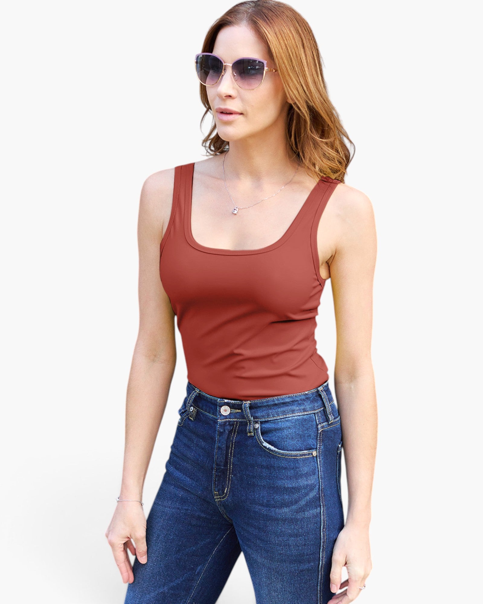 A woman modeling a rust-brown scoop-neck tank top paired with blue jeans and sunglasses, set against a plain white background.