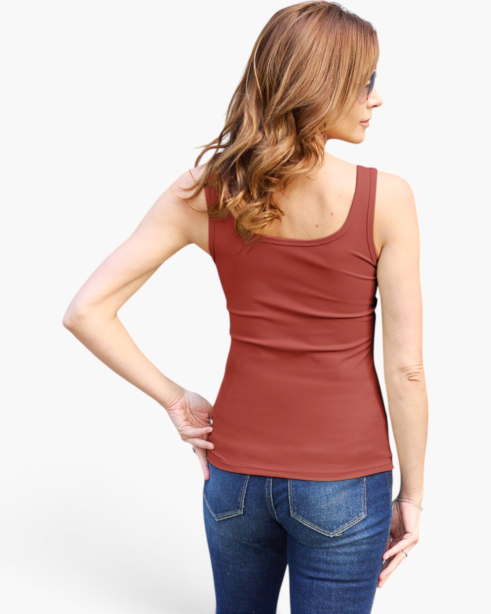 A woman shown from the back wearing a fitted sleeveless scoop-neck tank top in a muted terracotta/rust color, paired with blue jeans, against a plain light gray studio background.