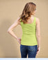 Woman wearing a green tank top and blue jeans against a beige background