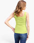A woman shown from the back wearing a bright lime green scoop-neck tank top and blue jeans against a plain white studio background.