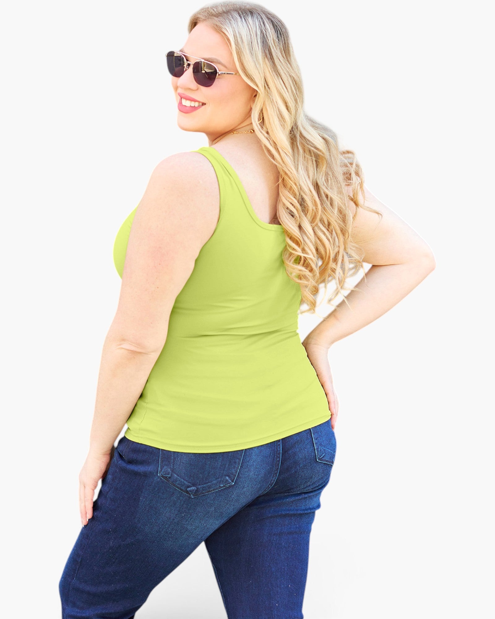 A woman modeling a bright lime green tank top and dark blue jeans, photographed from the back against a plain white studio background.