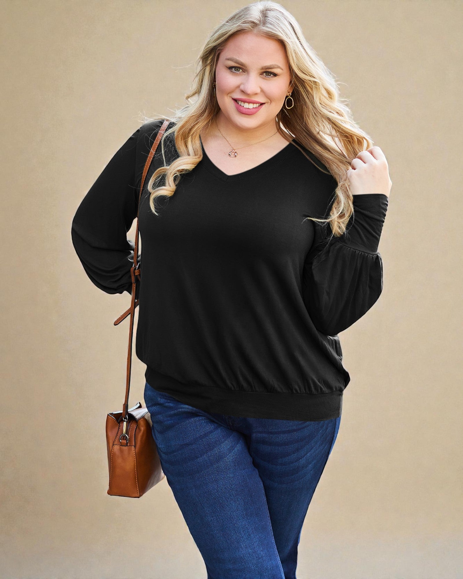 Woman wearing a black sweater and blue jeans with a brown handbag on a beige background