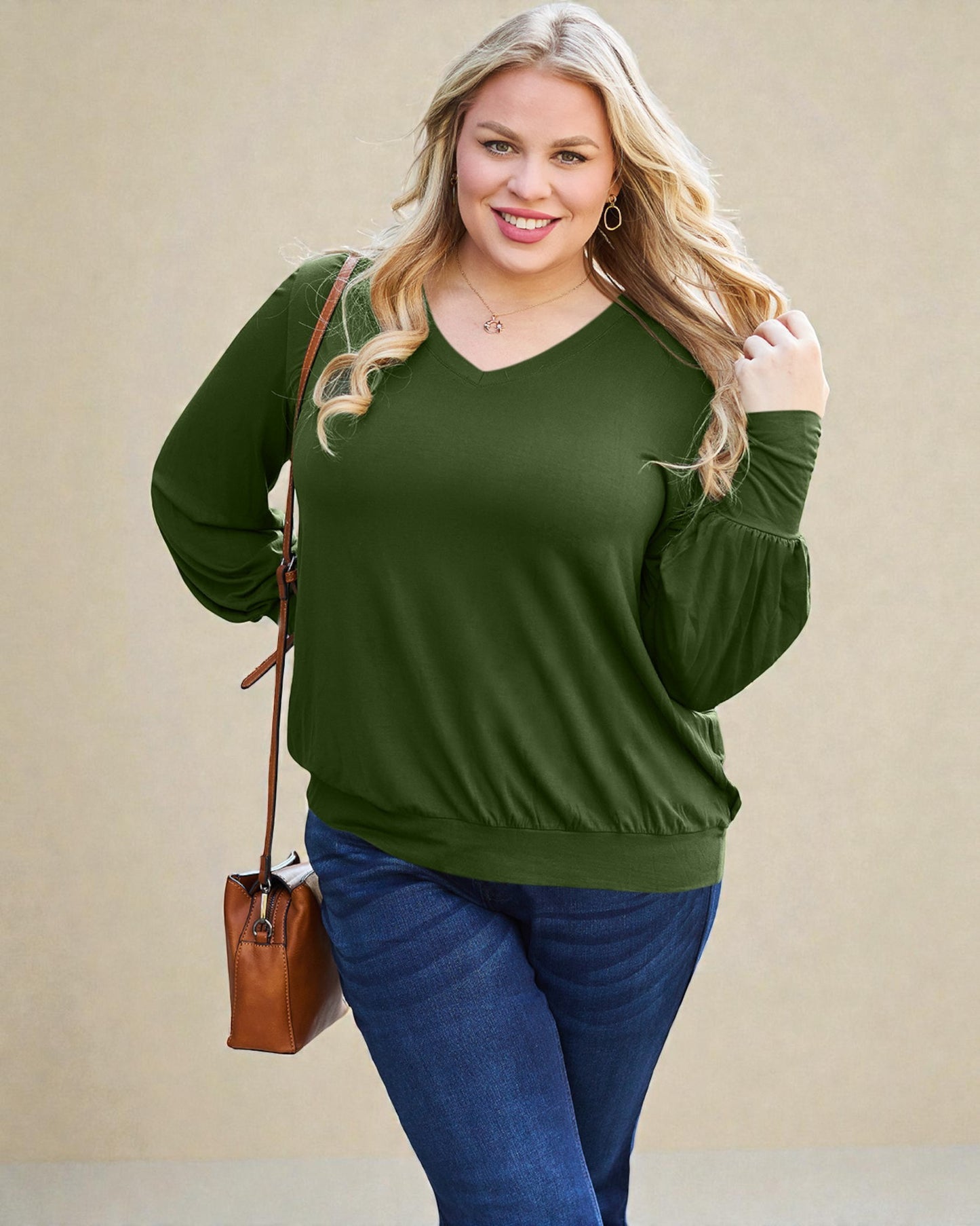 Woman wearing a green sweater and blue jeans against a beige background
