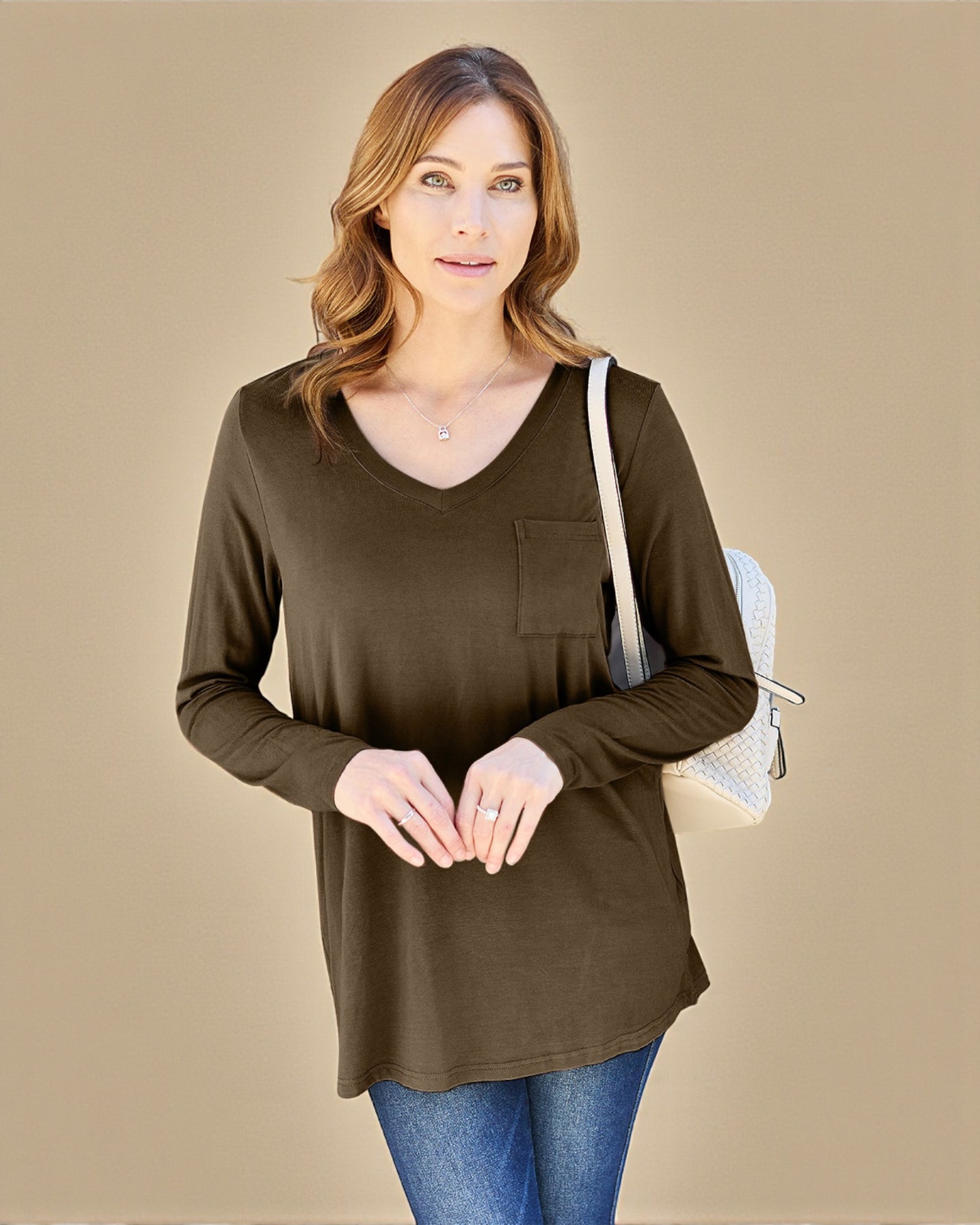 Woman wearing a brown long-sleeve top with a pocket on a beige background
