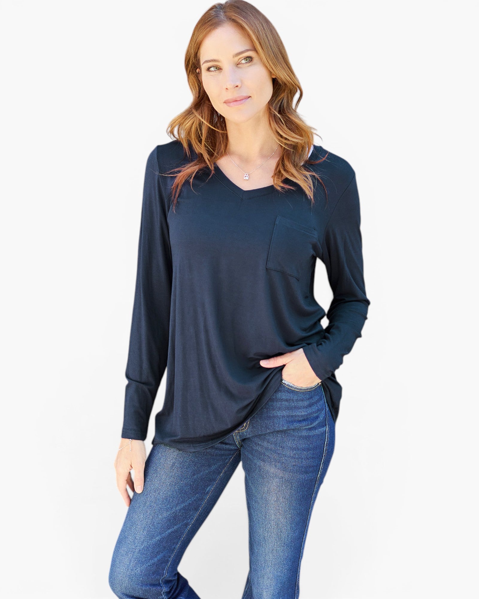 A woman modeling a dark navy blue long-sleeve top with a split neckline and a chest pocket, paired with blue jeans, against a plain white background.