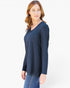 A woman modeling a dark navy blue long-sleeve V-neck top with a chest pocket, paired with blue jeans, against a plain white studio background.