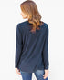 A woman with long brown hair is shown from the back wearing a navy blue long-sleeve top and blue jeans against a plain white background.