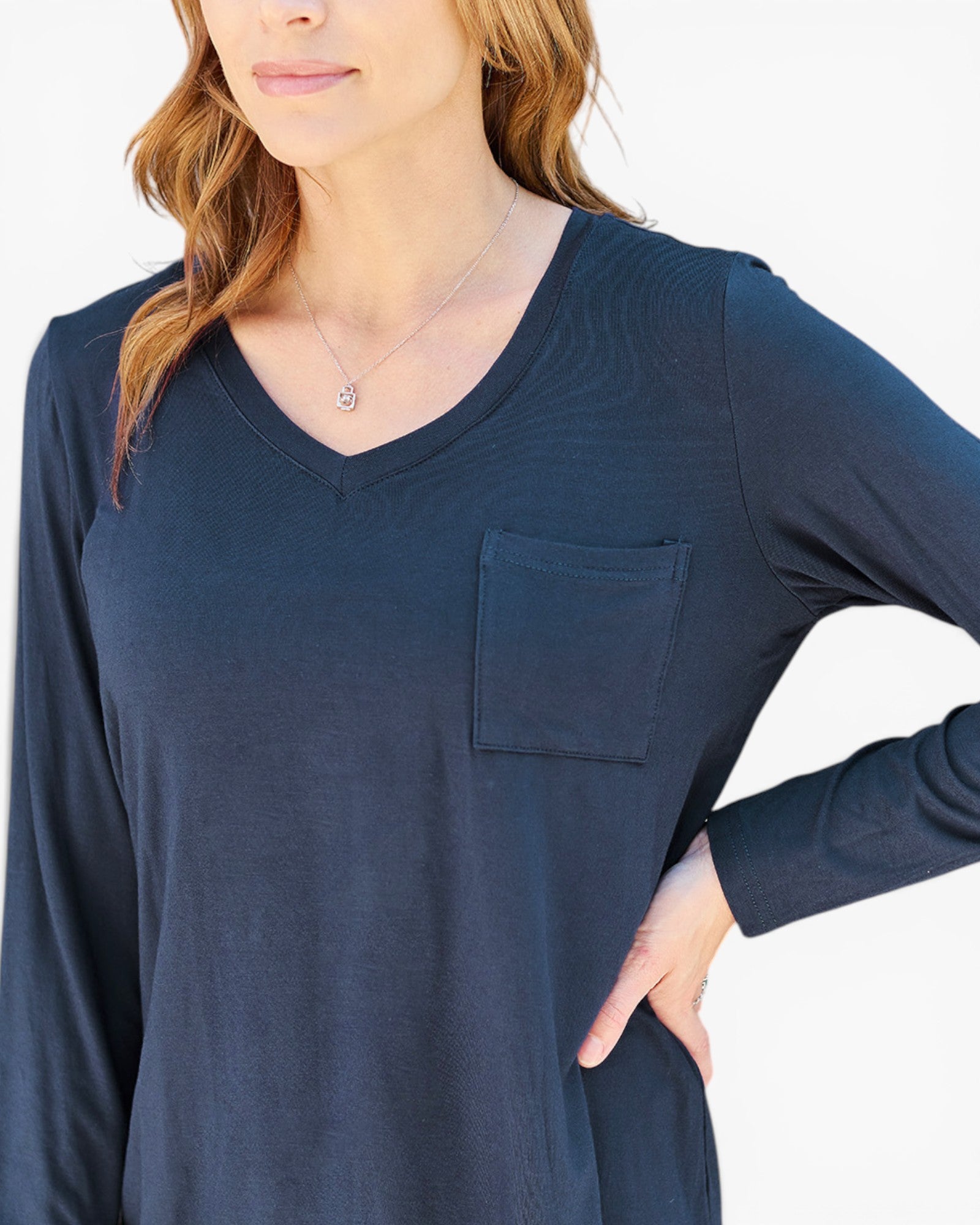 A woman wearing a dark navy blue long-sleeve V-neck top with a chest pocket, shown from the shoulders to the waist against a plain white background.
