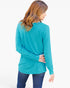 A woman shown from the back wearing a turquoise long-sleeve top and dark blue jeans against a plain white background.