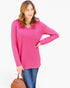 A woman modeling a bright pink long-sleeve tunic top with a chest pocket, paired with blue jeans, holding a brown leather handbag against a plain white background.
