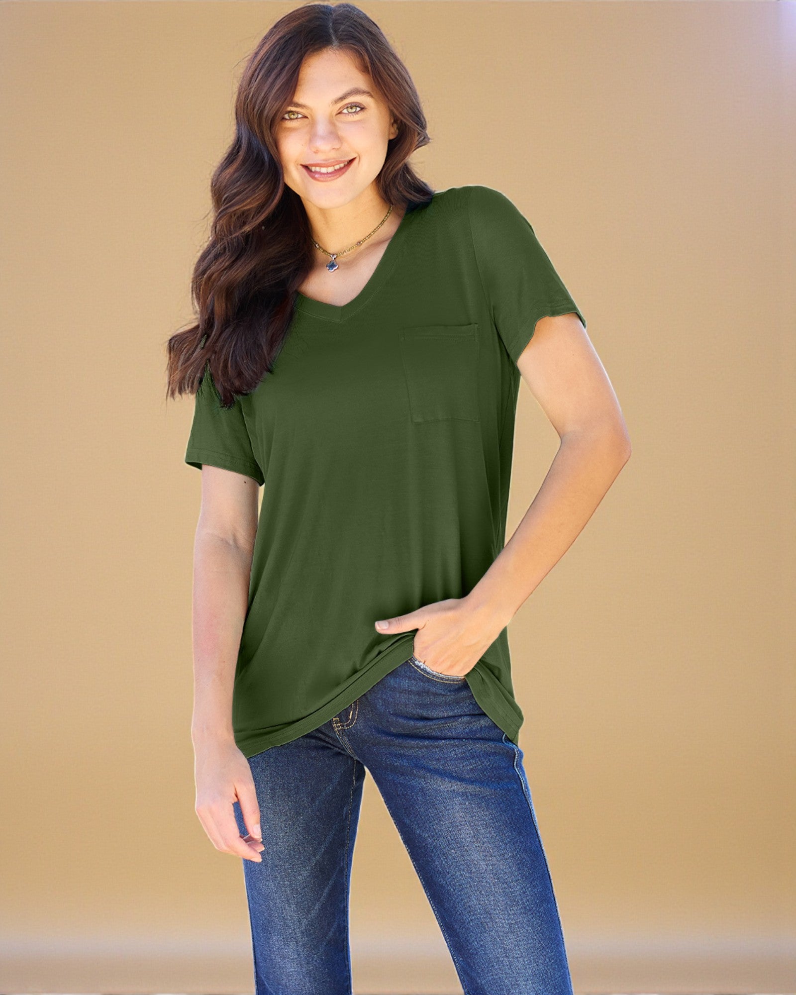Woman wearing a green t-shirt and blue jeans against a beige background