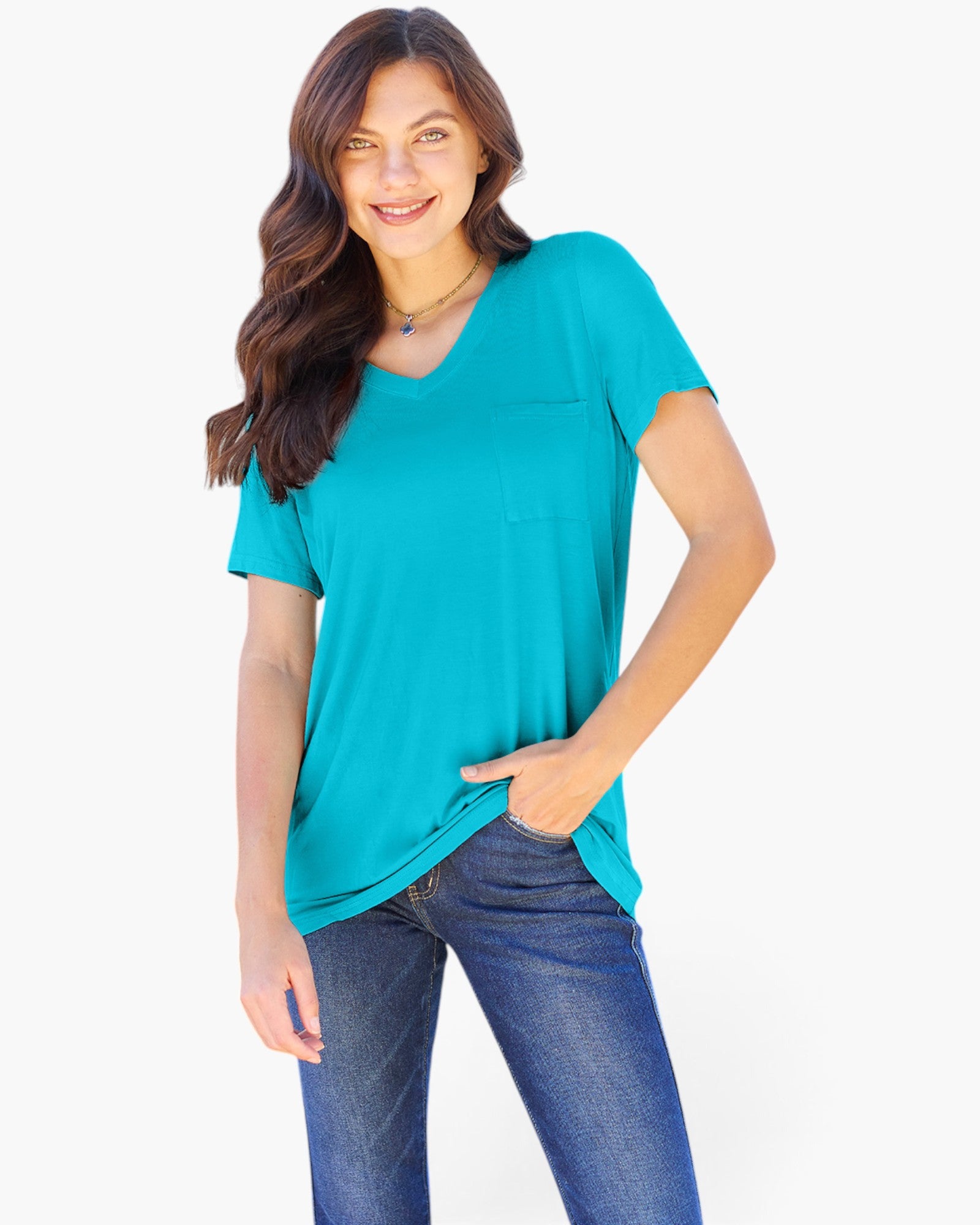 A woman modeling a bright turquoise short-sleeve V-neck top with a chest pocket, paired with blue jeans, against a plain white background.