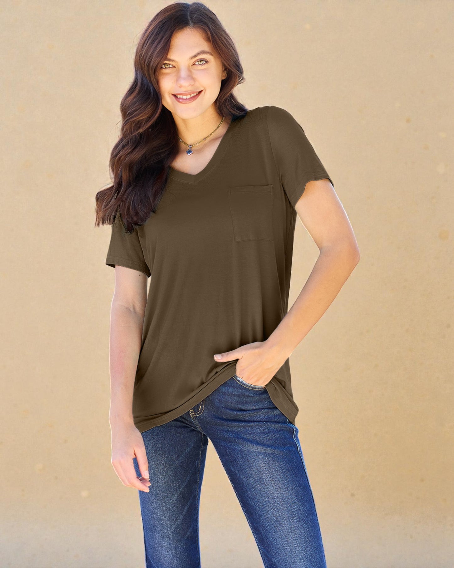 Woman wearing an olive green t-shirt and blue jeans against a beige background
