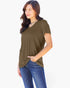A woman wearing a short-sleeve V-neck top in olive green with a chest pocket, paired with blue jeans, photographed against a plain light background.