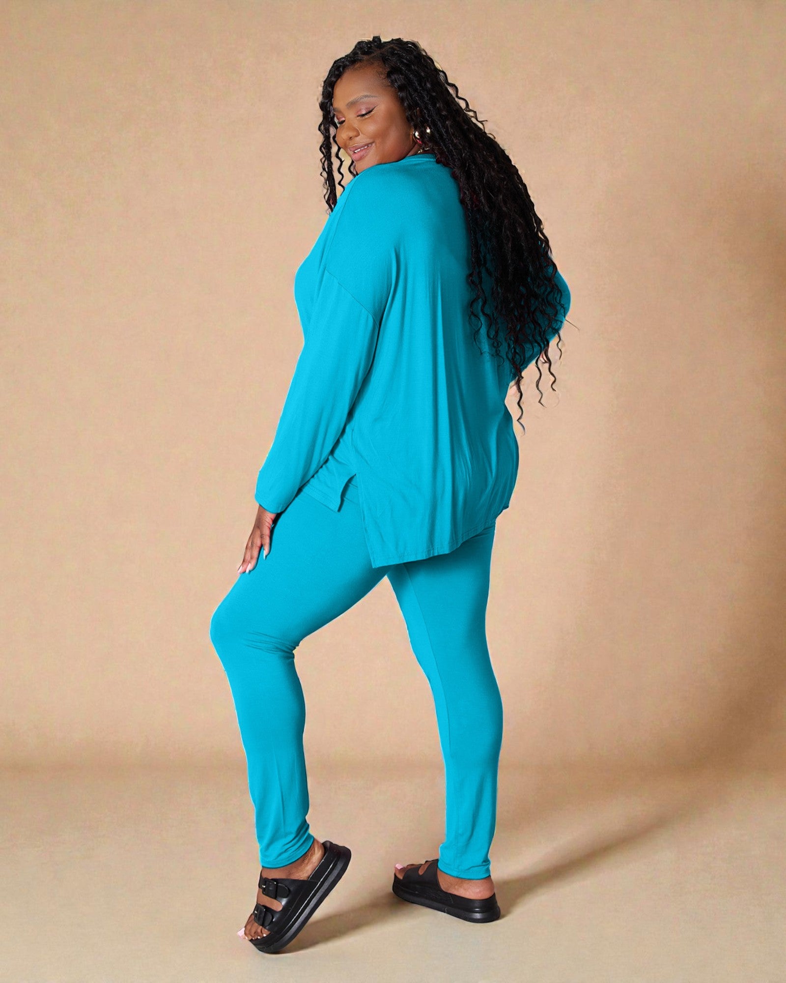 Woman wearing a turquoise outfit against a beige background