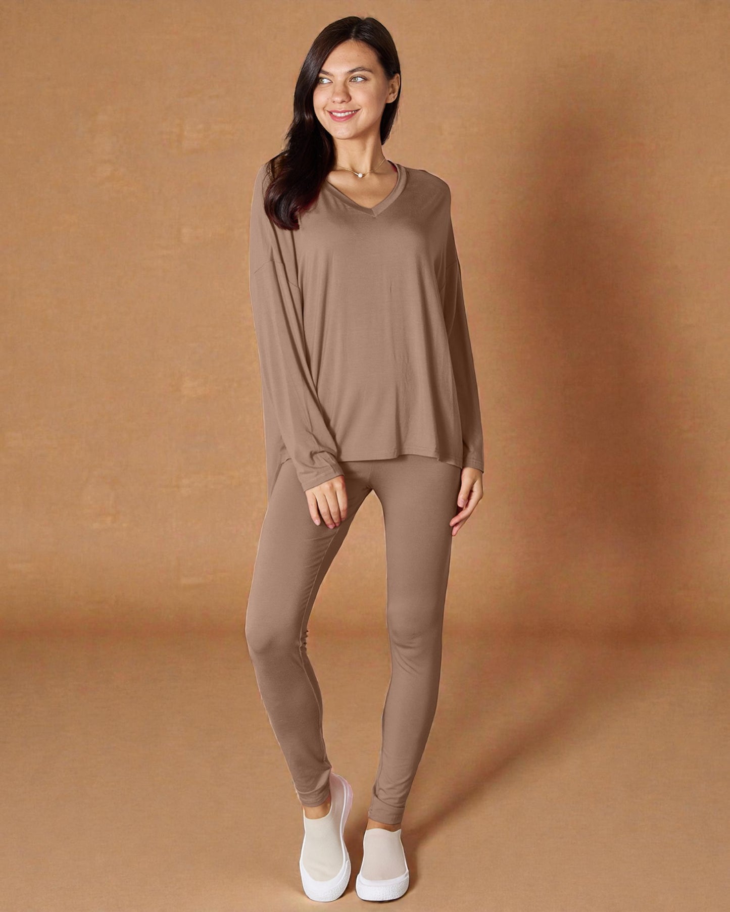 Woman wearing a brown long-sleeve top and leggings against a brown background
