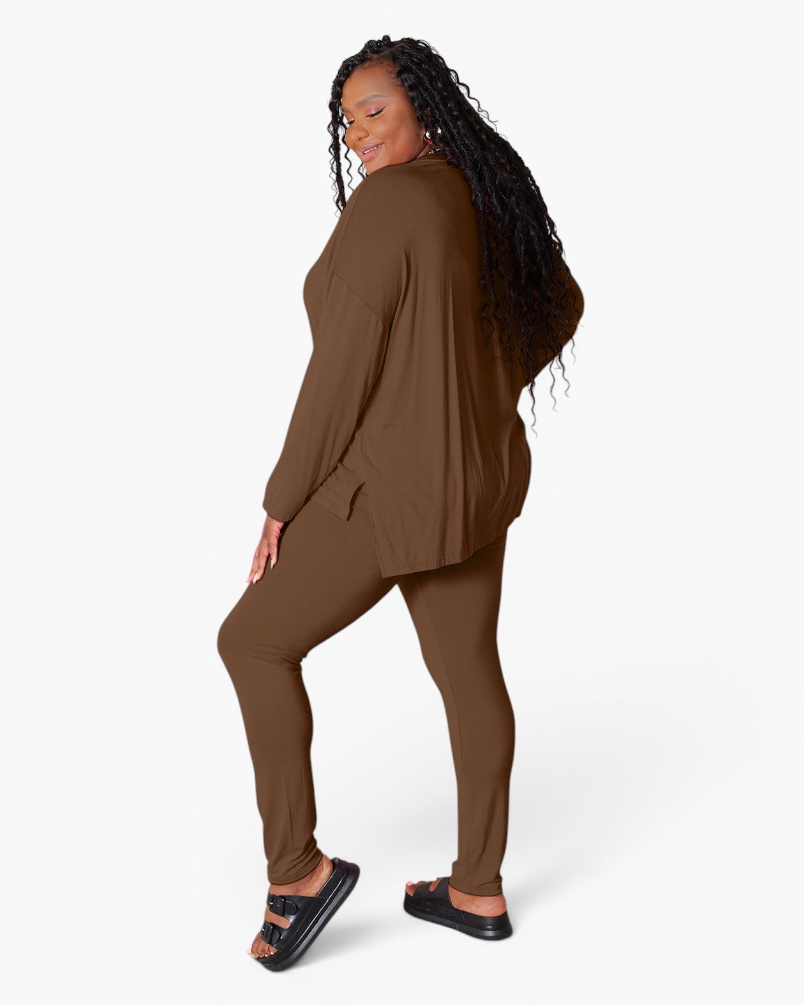 A woman modeling a matching brown lounge set consisting of a long-sleeve top and leggings, shown from a side-back angle against a plain white studio background.