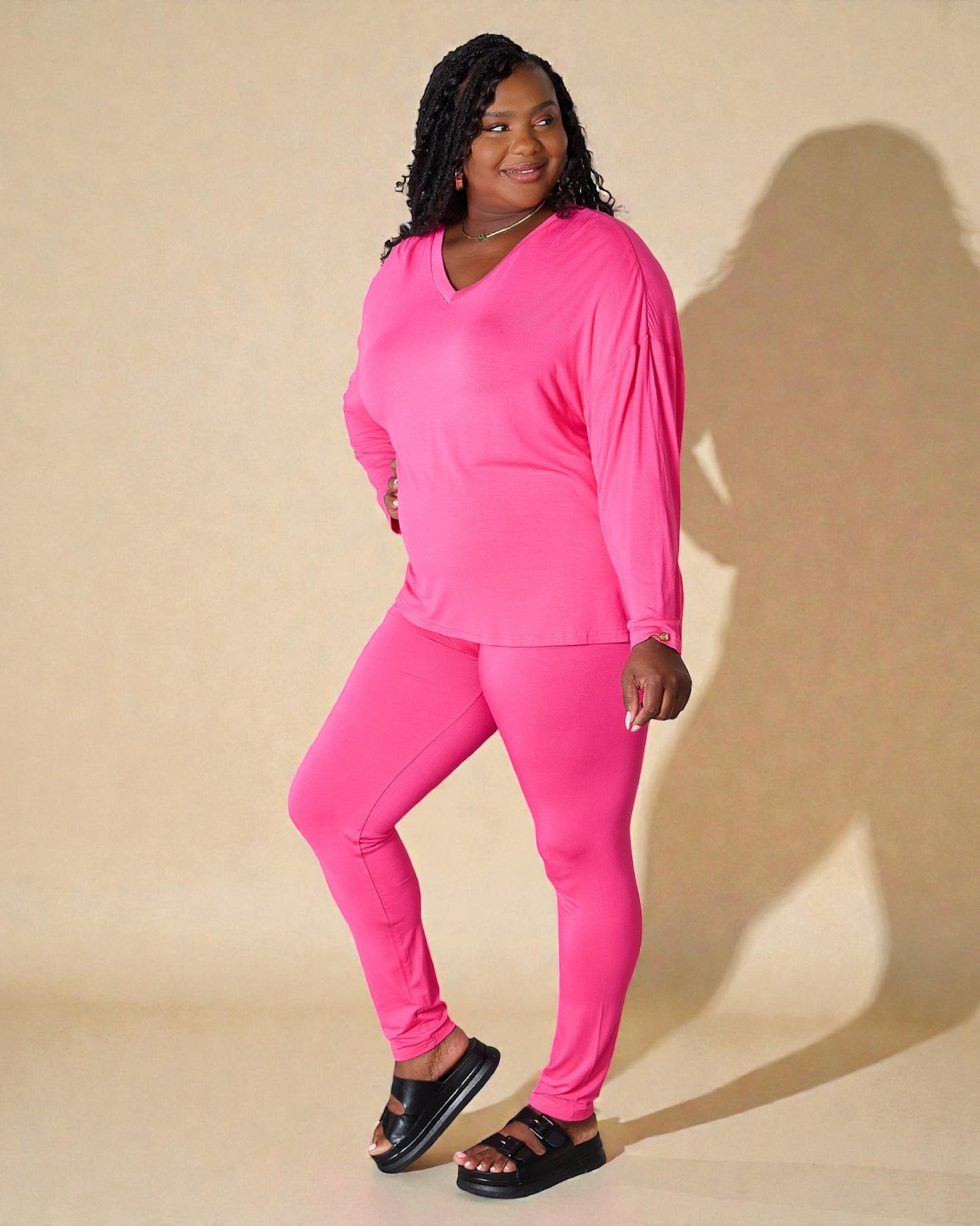 Person wearing a bright pink outfit on a beige background