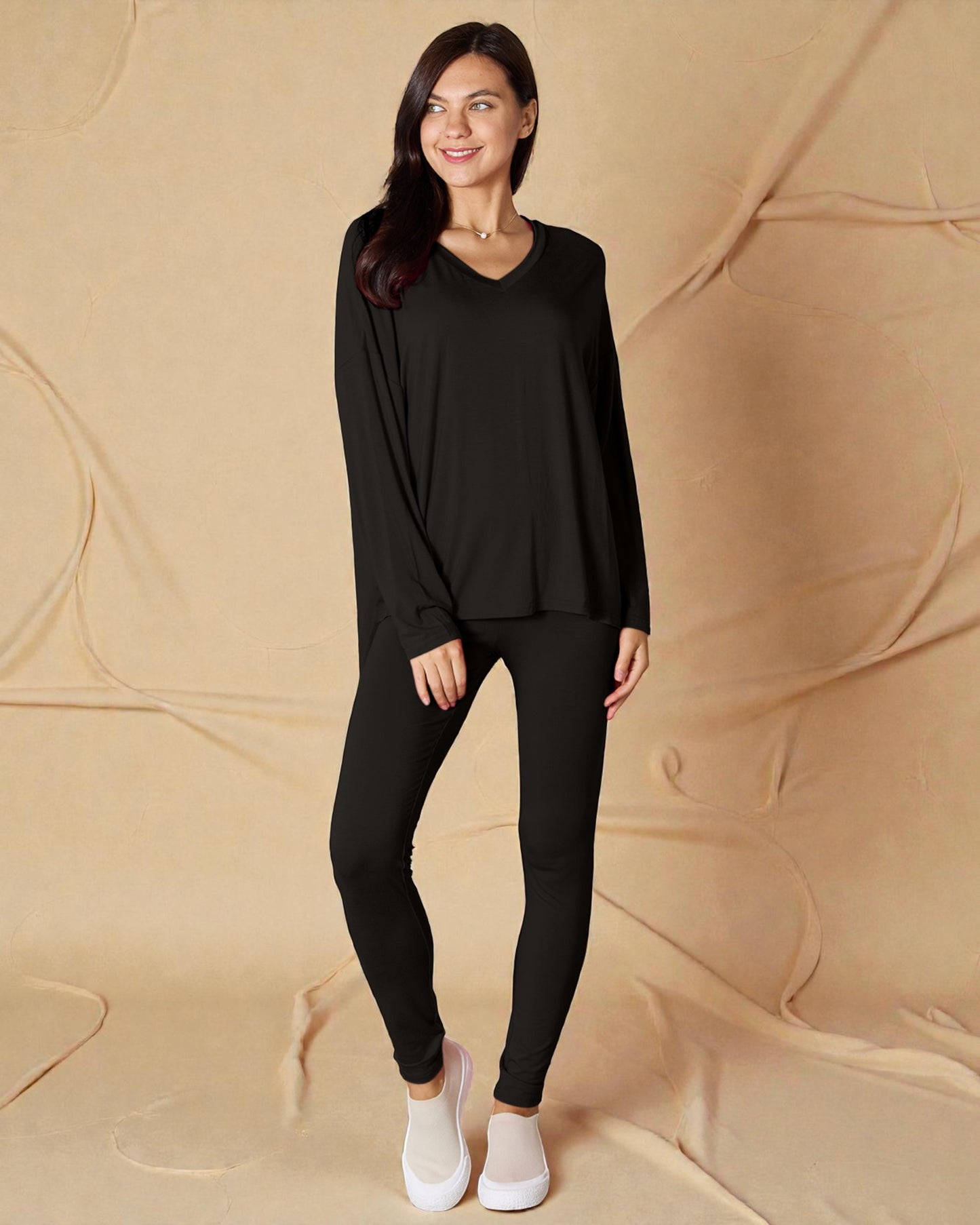 Woman wearing a black outfit standing against a beige background